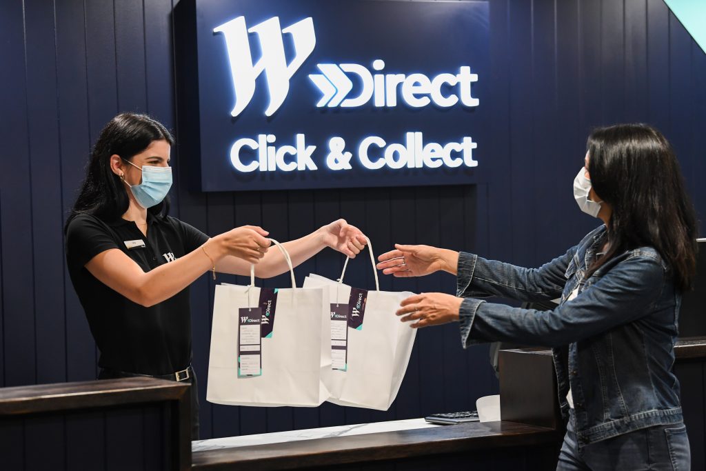 Two women where masks, one woman is receiving her purchases